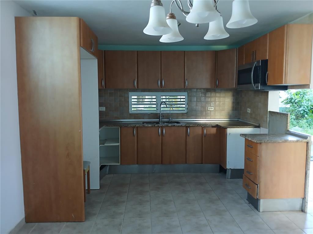 A kitchen with wood cabinets, tiled floors, a double sink, and a built-in microwave — CALLE RIO PITAHAYA RIVER EDGE HILLS UNIT 120, LUQUILLO, PR