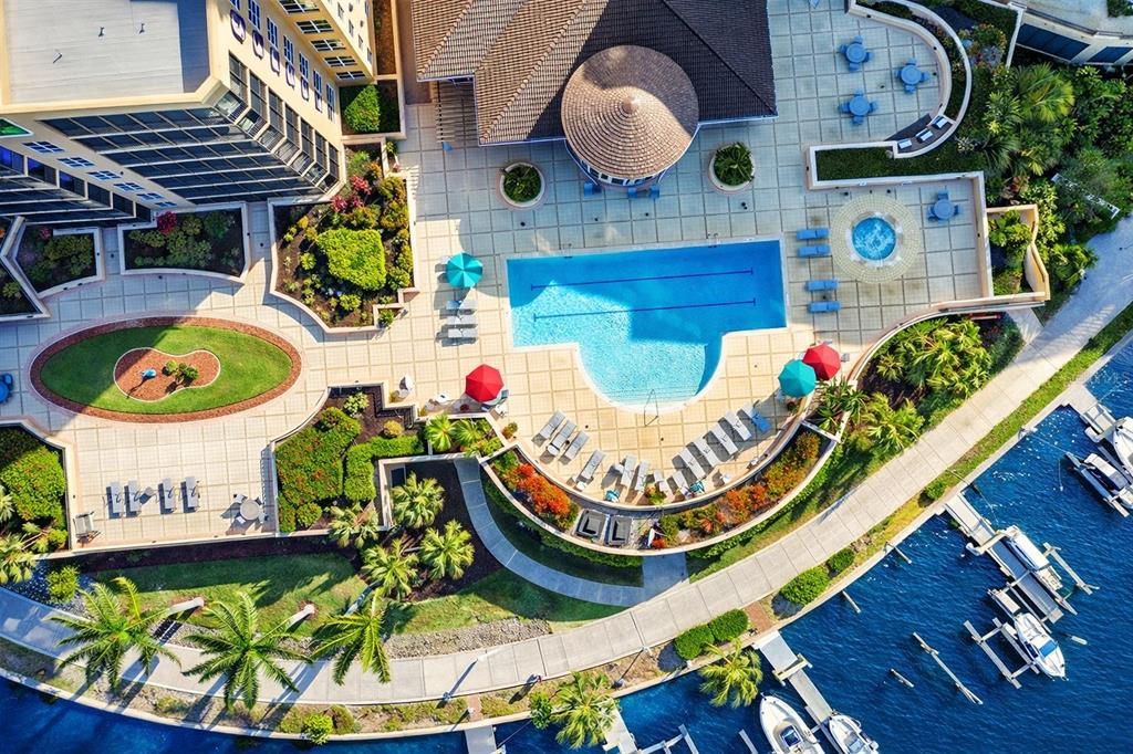 An aerial view shows a resort-style swimming pool, hot tub, and marina with docked boats — 3321 SUNSET KEY CIRCLE UNIT 502, PUNTA GORDA, FL
