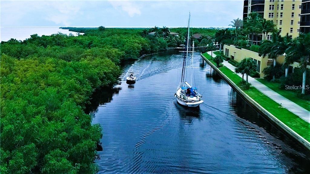 An aerial view shows a sailboat and a small motorboat traveling down a narrow canal — 3321 SUNSET KEY CIRCLE UNIT 502, PUNTA GORDA, FL