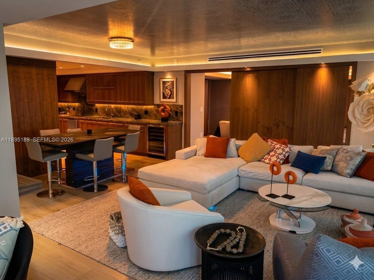 A modern open-concept living room features a white sectional sofa, kitchen area, and dining island — 9401 Collins Ave # 305, Surfside FL 33154, SURFSIDE, FL