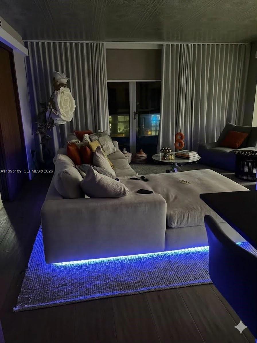 A living room features a large sectional, armchairs, a glass coffee table, and floor-to-ceiling windows — 9401 Collins Ave # 305, Surfside FL 33154, SURFSIDE, FL