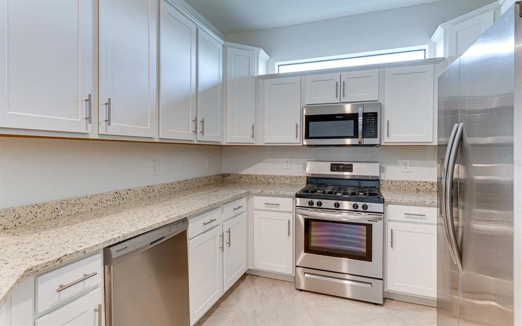 A kitchen with white cabinets, granite countertops, and stainless steel appliances — 5343 WHITE SAND COVE, BRADENTON, FL