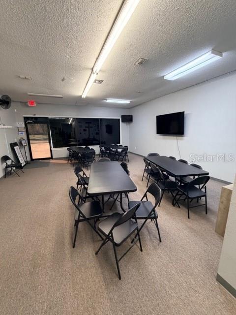 A multi-purpose room features folding tables, black chairs, fluorescent lighting, and a wall-mounted television — 320 S SPRING GARDEN AVENUE, DELAND, FL
