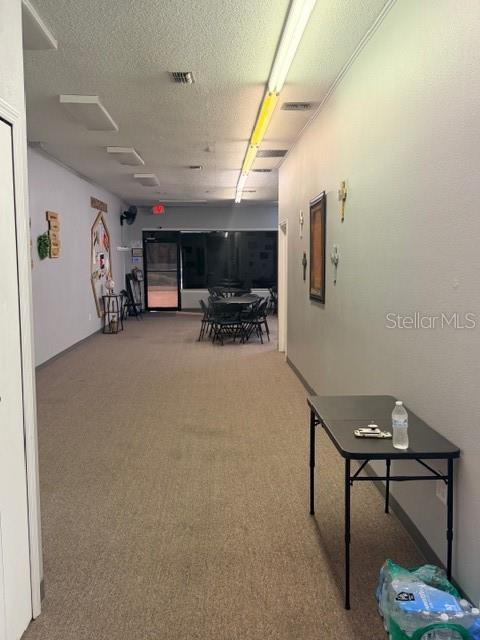 A long, carpeted room features a folding table in the foreground and chairs in back — 320 S SPRING GARDEN AVENUE, DELAND, FL