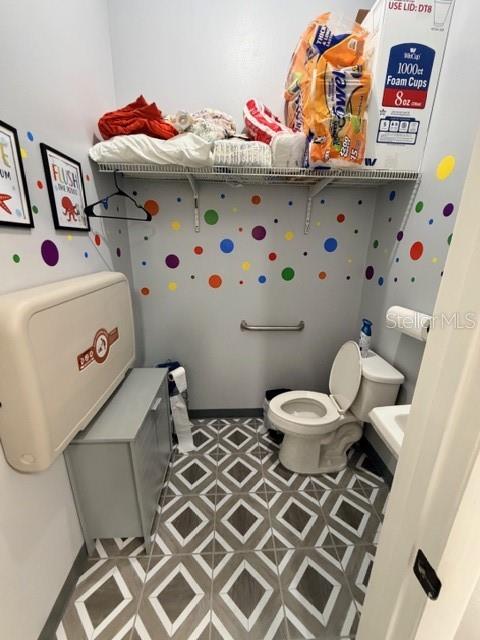 A small restroom features a wall-mounted changing table, a toilet, and colorful polka-dot wall decals — 320 S SPRING GARDEN AVENUE, DELAND, FL