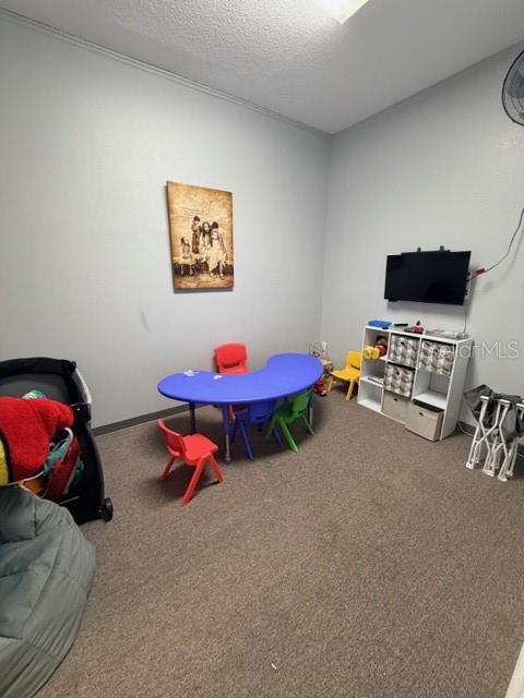 A playroom features a blue crescent-shaped table, colorful chairs, a television, and storage shelving — 320 S SPRING GARDEN AVENUE, DELAND, FL