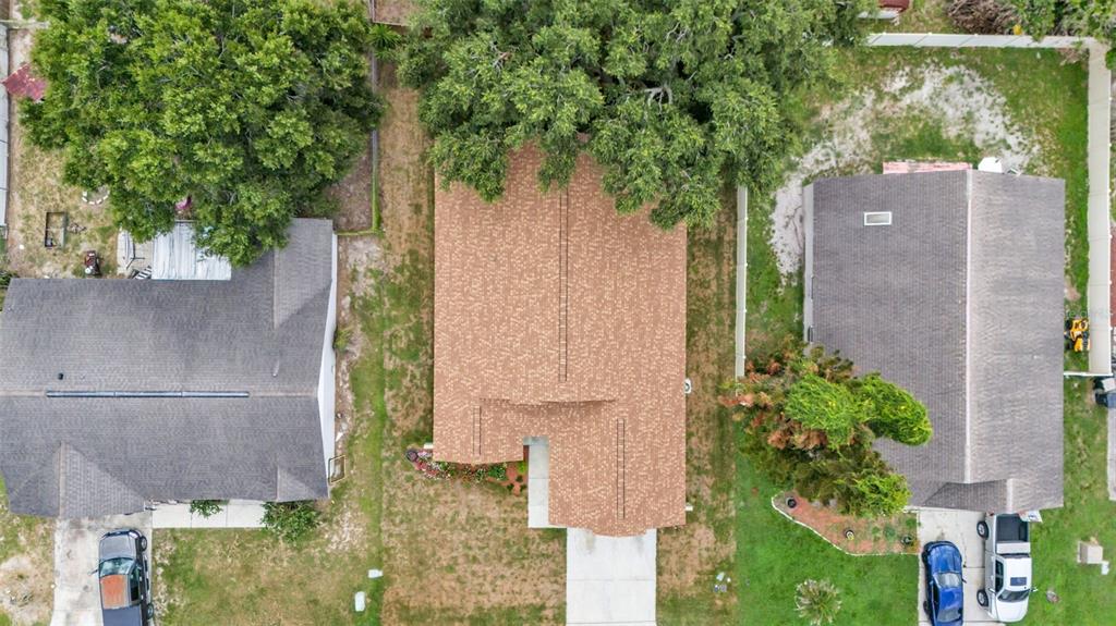 An aerial view shows three houses with shingled roofs surrounded by lawns and large trees — 419 SAINT ANNS DRIVE, WINTER HAVEN, FL