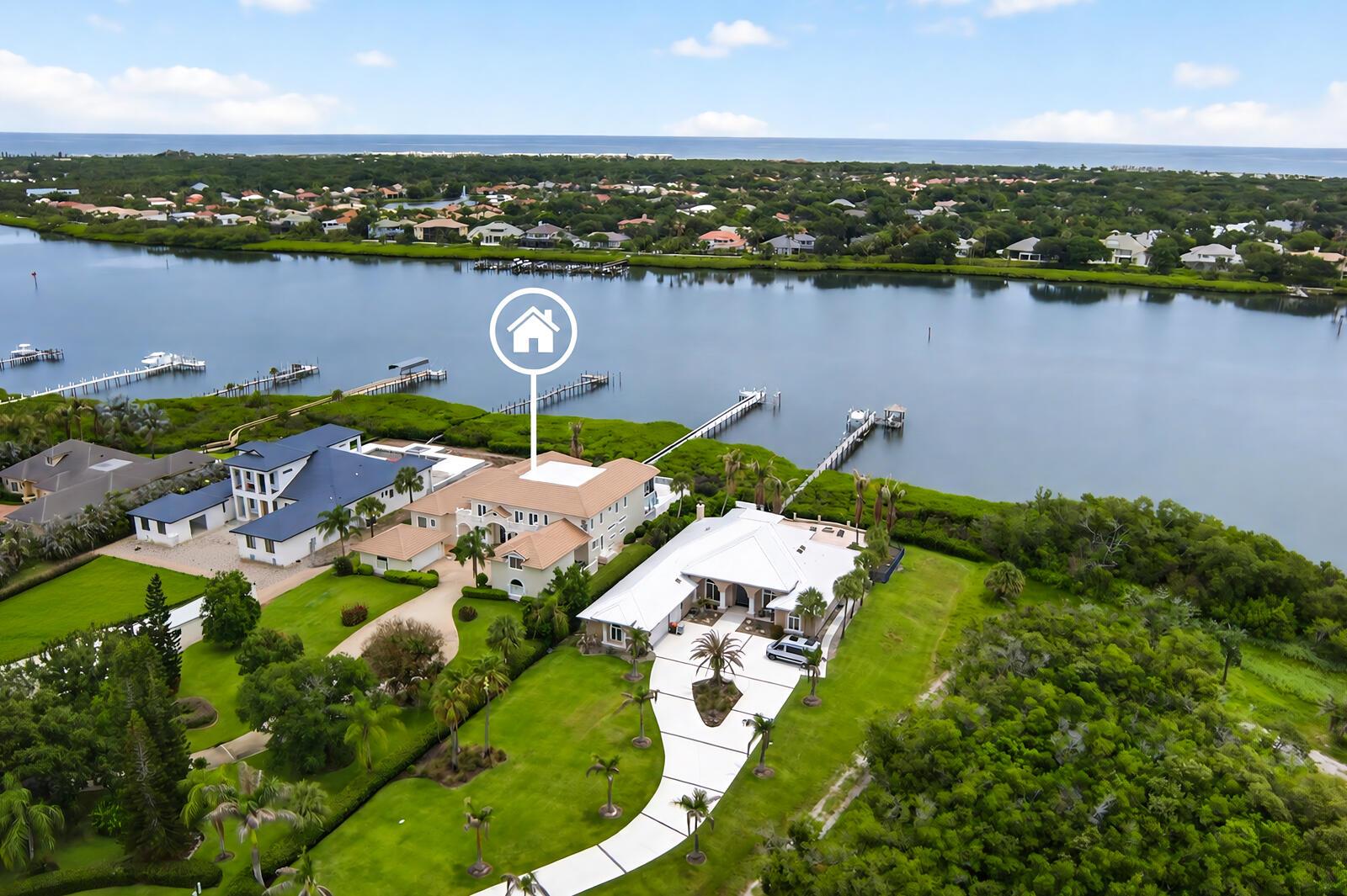 An aerial view shows two large waterfront houses with private docks along a calm bay — VERO BEACH, FL