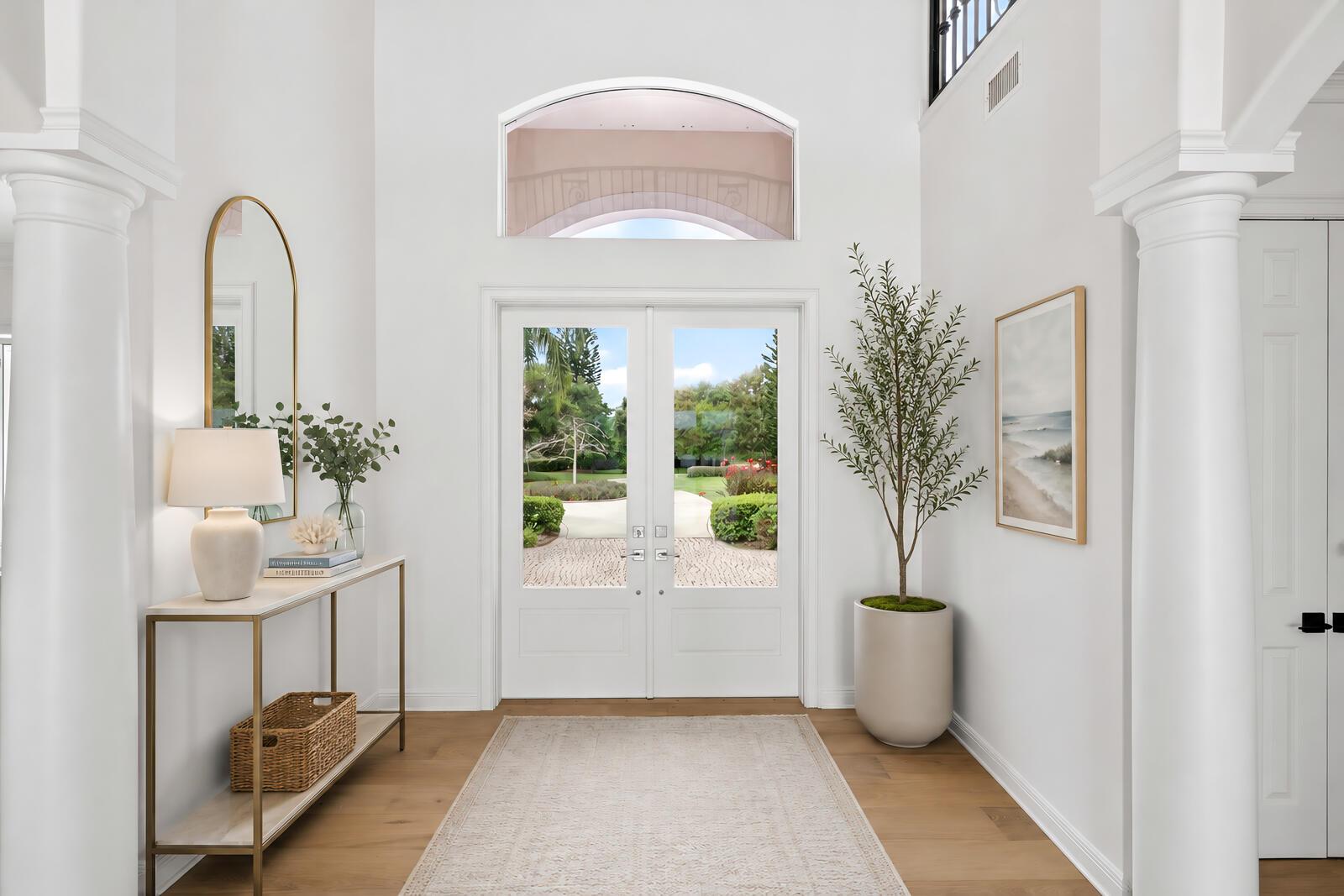A bright entryway features white walls, a double glass door, columns, and a console table — VERO BEACH, FL