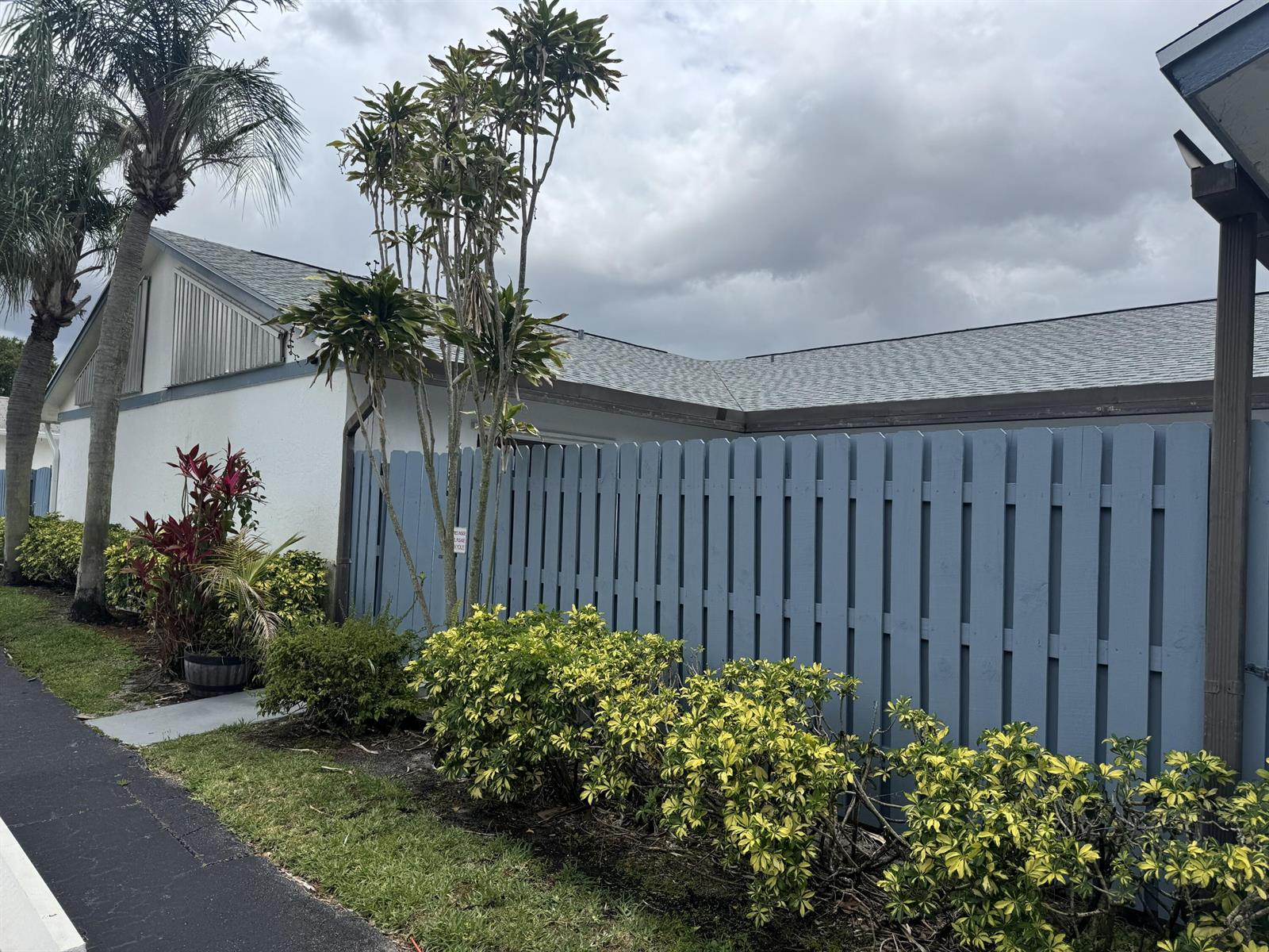 A blue wooden fence stands in front of a white house with a gray roof — 1204 Timberlane Circle # 12d, FL 33463, FL