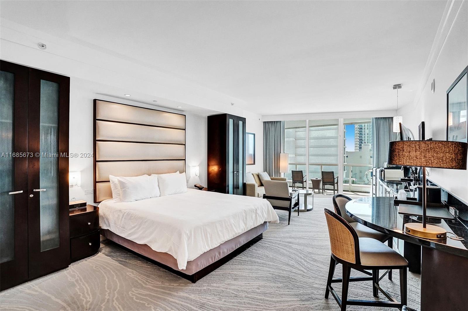 A hotel-style bedroom features a king bed, a seating area, and a balcony with city views — 4391 Collins Ave # 915, Miami Beach FL 33140, MIAMI BEACH, FL