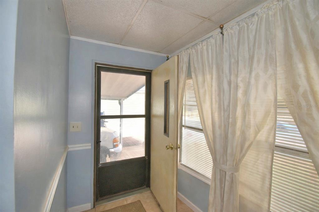 An interior entryway features light blue walls, a screen door, and white curtains over windows — 4173 ROLLING OAKS DRIVE, WINTER HAVEN, FL