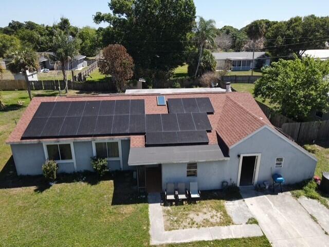 An aerial view of a single-story house with a large solar panel array on the roof — 4904 Myrtle Drive, Fort Pierce FL 34982, FORT PIERCE, FL