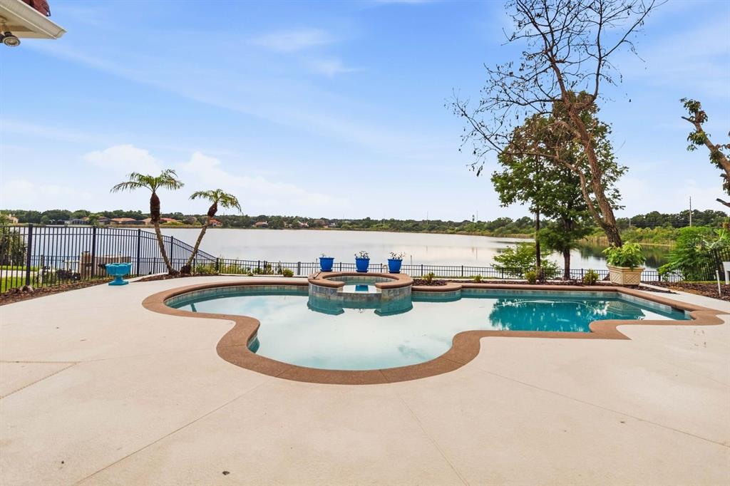 A swimming pool and spa overlook a lake from a concrete patio with a fence — 8310 TIVOLI DRIVE, ORLANDO, FL