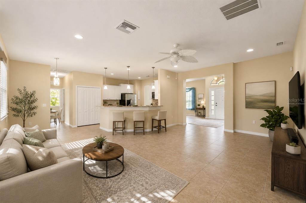 A living room with tile floors, a kitchen island with bar stools, and a sofa — 13589 HUNTERS POINT STREET, SPRING HILL, FL