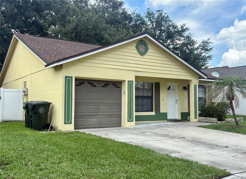 A yellow single-story house with a brown garage door and a white front door — 1021 ALPUG AVENUE, OVIEDO, FL