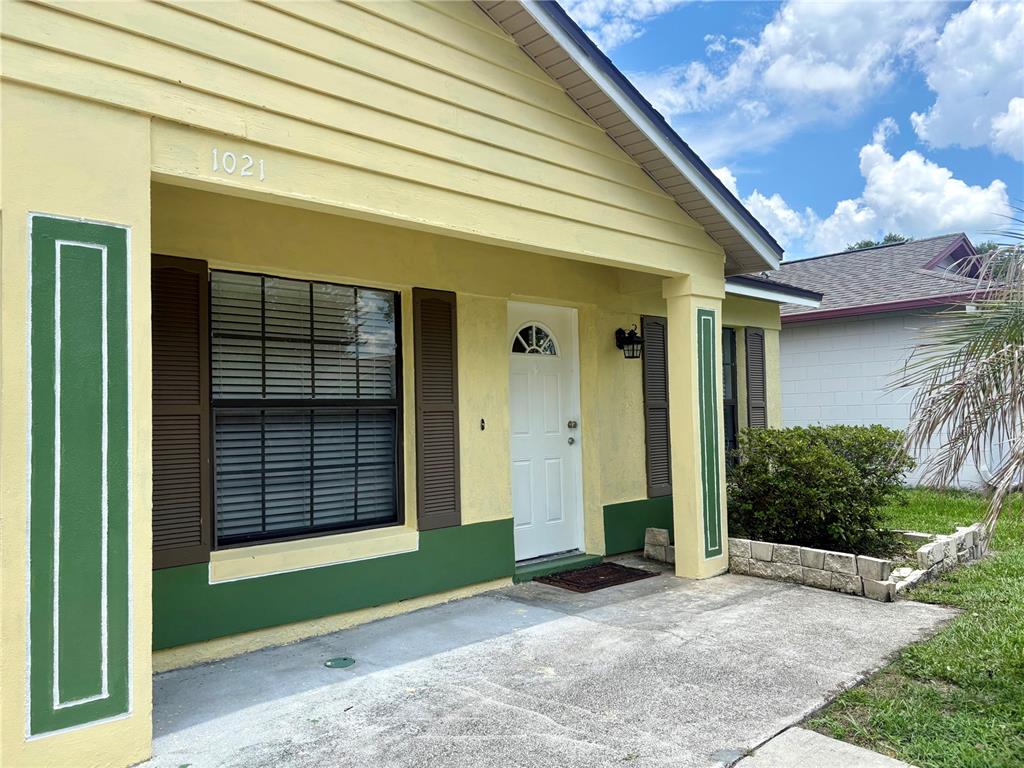 A yellow house exterior features a front porch, a white door, and green trim — 1021 ALPUG AVENUE, OVIEDO, FL