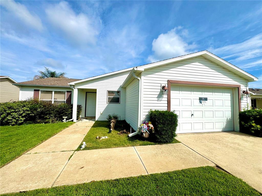 A single-story house with white vinyl siding, a one-car garage, and a concrete driveway — 892 NASH LOOP, THE VILLAGES, FL
