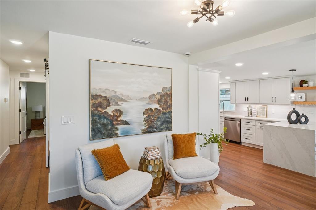 Two armchairs with orange pillows sit before a landscape painting in a modern home interior — 3123 W LA SALLE STREET, TAMPA, FL