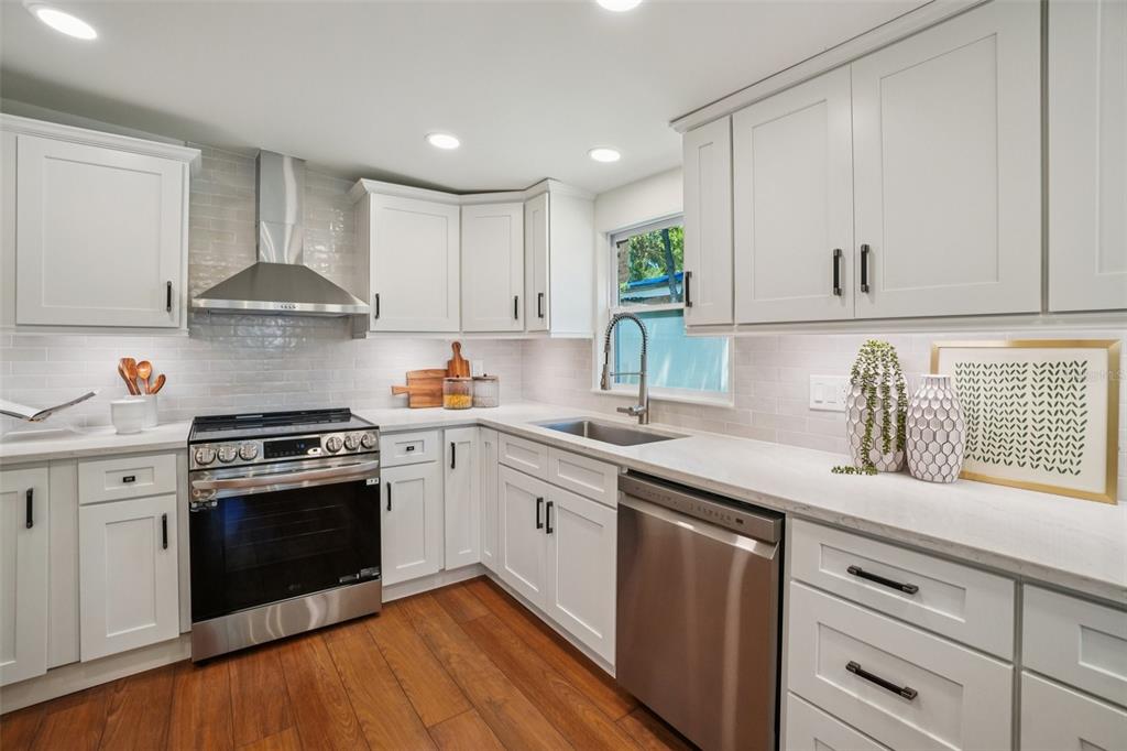 A kitchen with white cabinets, stainless steel appliances, light countertops, and wood flooring — 3123 W LA SALLE STREET, TAMPA, FL