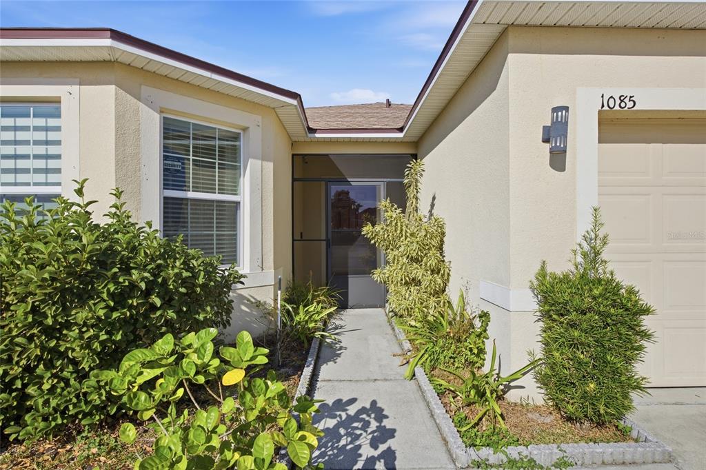 The exterior of a house features a concrete walkway leading to a screened front entryway — 1085 BRENTON MANOR DRIVE, WINTER HAVEN, FL
