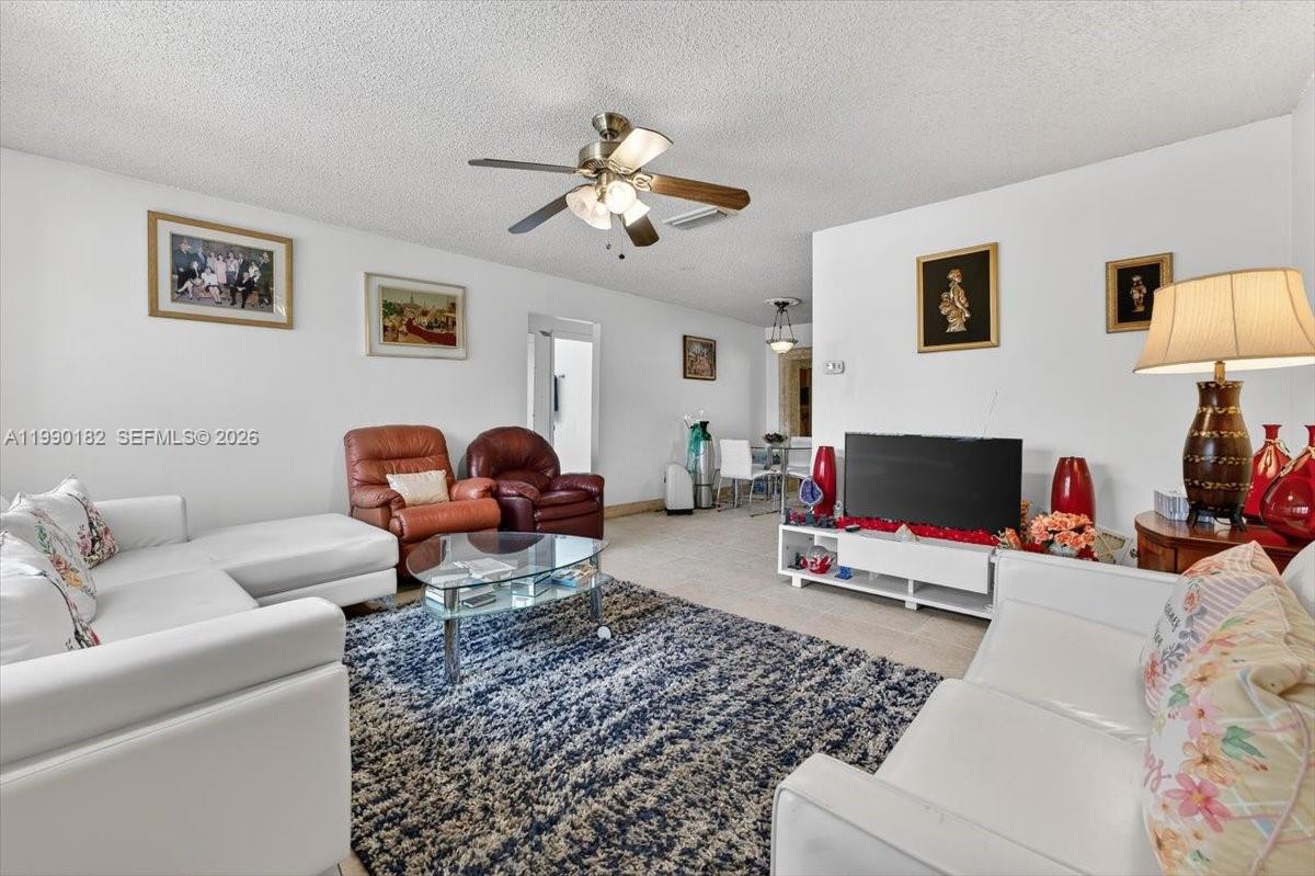 A living room features white sofas, a glass coffee table, and a dark blue rug — 1125 NW 69th Ave, Margate FL 33063, MARGATE, FL