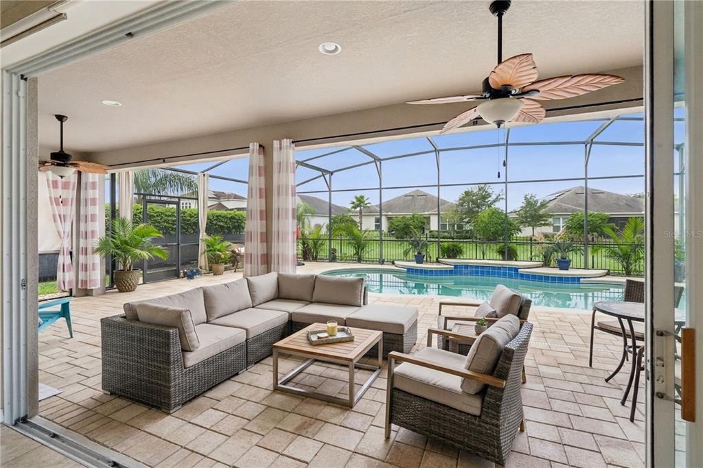 A covered patio features a sectional sofa, chairs, and a swimming pool inside a screen enclosure — 14038 JOMATT LOOP, WINTER GARDEN, FL
