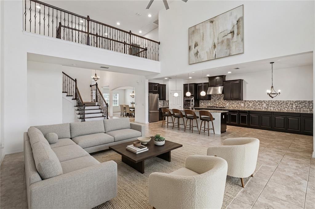 An open-concept living room and kitchen with high ceilings, dark cabinetry, and a lofted balcony — 14038 JOMATT LOOP, WINTER GARDEN, FL