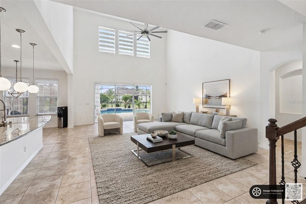 A spacious living room with high ceilings, tile floors, a sectional sofa, and pool views — 14038 JOMATT LOOP, WINTER GARDEN, FL