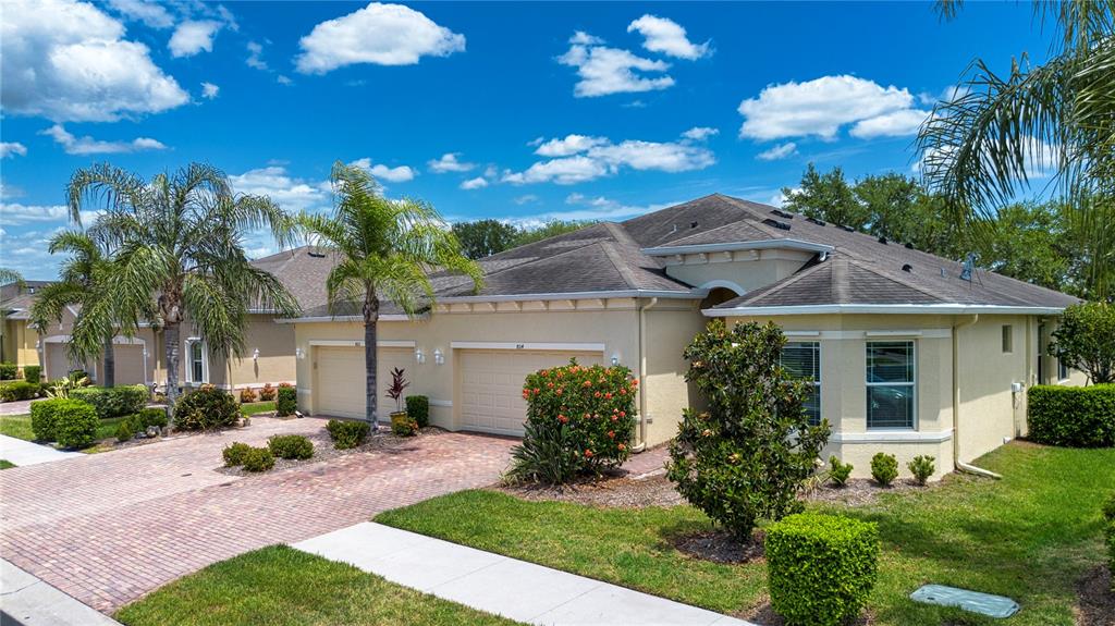 An aerial view shows three suburban homes with shingled roofs overlooking a large pond — 804 CHIPPER DRIVE, SUN CITY CENTER, FL