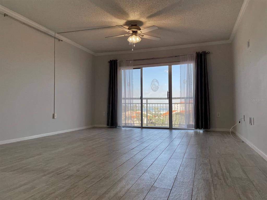 An empty room with light wood-look tile flooring, a ceiling fan, and sliding glass balcony doors — 4900 BRITTANY DRIVE S UNIT 509, ST PETERSBURG, FL
