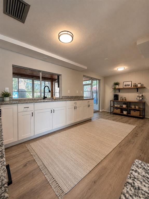 A kitchen features white cabinets, granite countertops, a large area rug, and a coffee station — 3507 LANDALE DRIVE, HOLIDAY, FL