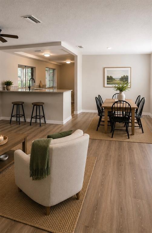 A living room with a beige armchair leads to an open kitchen and dining area — 3507 LANDALE DRIVE, HOLIDAY, FL