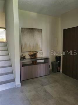 An entryway features a staircase, a wooden console table with wall art, and tile flooring — 322 Beach Village BEACH VILLAGE - CANDELERO DRIVE - UNIT 322, HUMACAO, PR