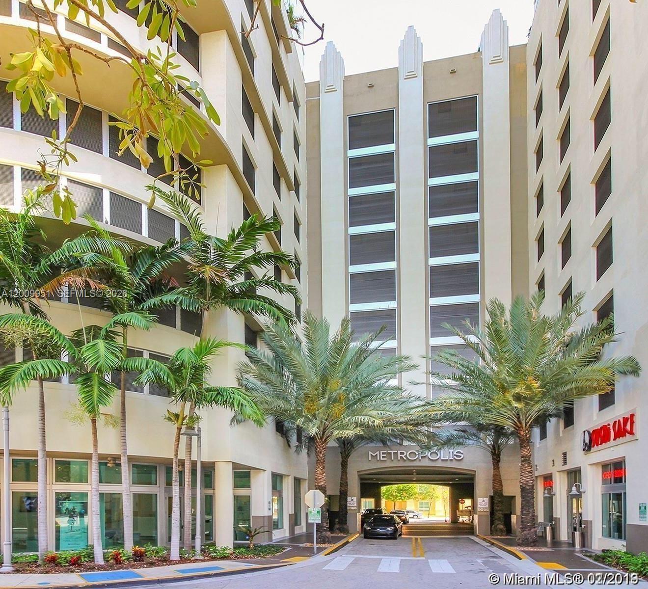 The exterior of a multi-story apartment building features a central driveway, palm trees, and signage — 9066 SW 73rd Ct # 1910, Miami FL 33156, MIAMI, FL