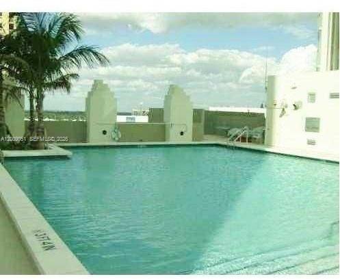 A rooftop swimming pool with a palm tree and light-colored architectural structures under a cloudy sky — 9066 SW 73rd Ct # 1910, Miami FL 33156, MIAMI, FL