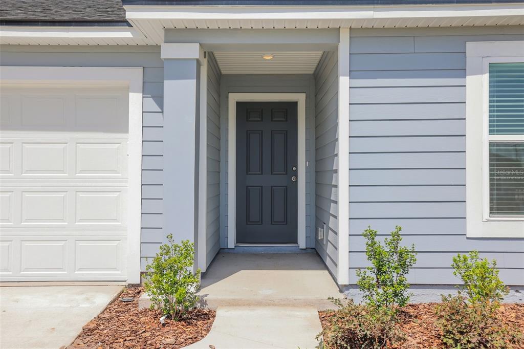 A gray front door is centered under a covered porch next to a garage — 5776 LAGOON CRUISE WAY, JACKSONVILLE, FL