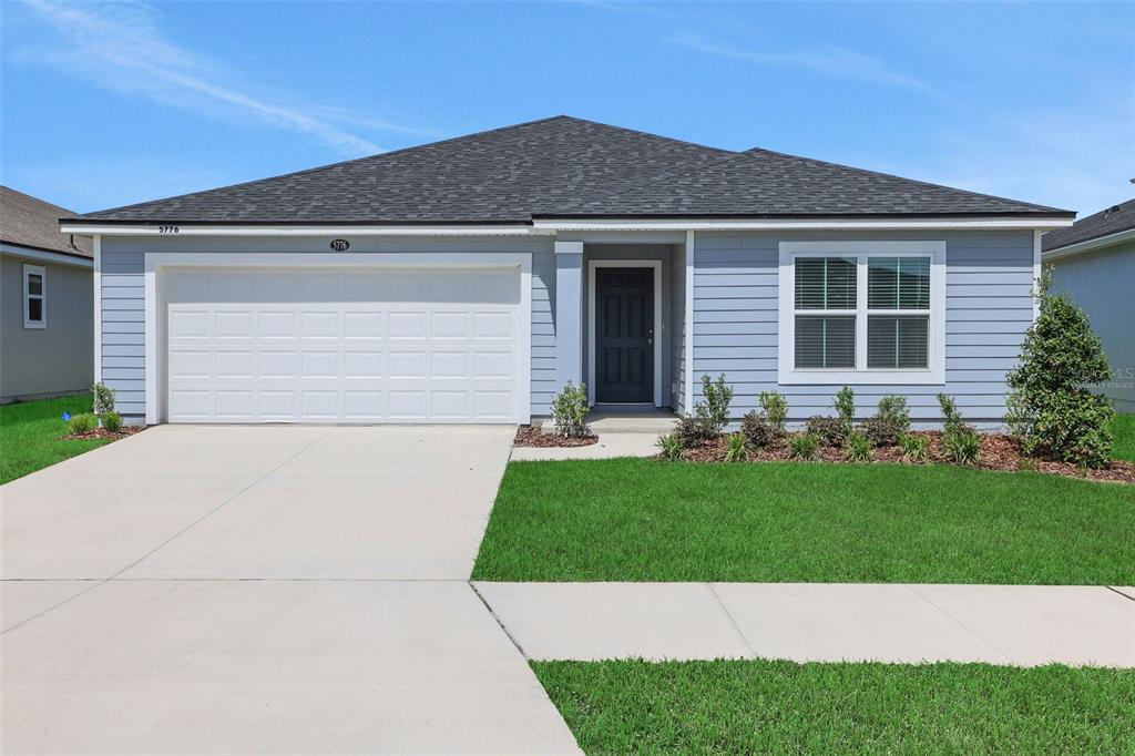 A single-story house with light blue siding, a two-car garage, and a dark shingled roof — 5776 LAGOON CRUISE WAY, JACKSONVILLE, FL