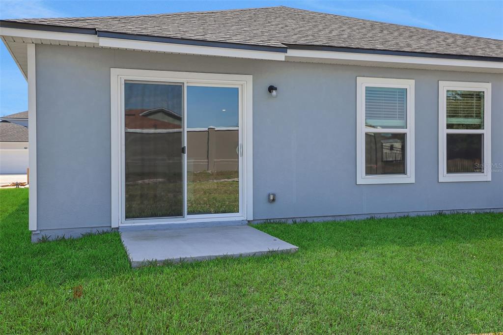 The exterior rear view of a gray house features a sliding glass door and windows — 5776 LAGOON CRUISE WAY, JACKSONVILLE, FL