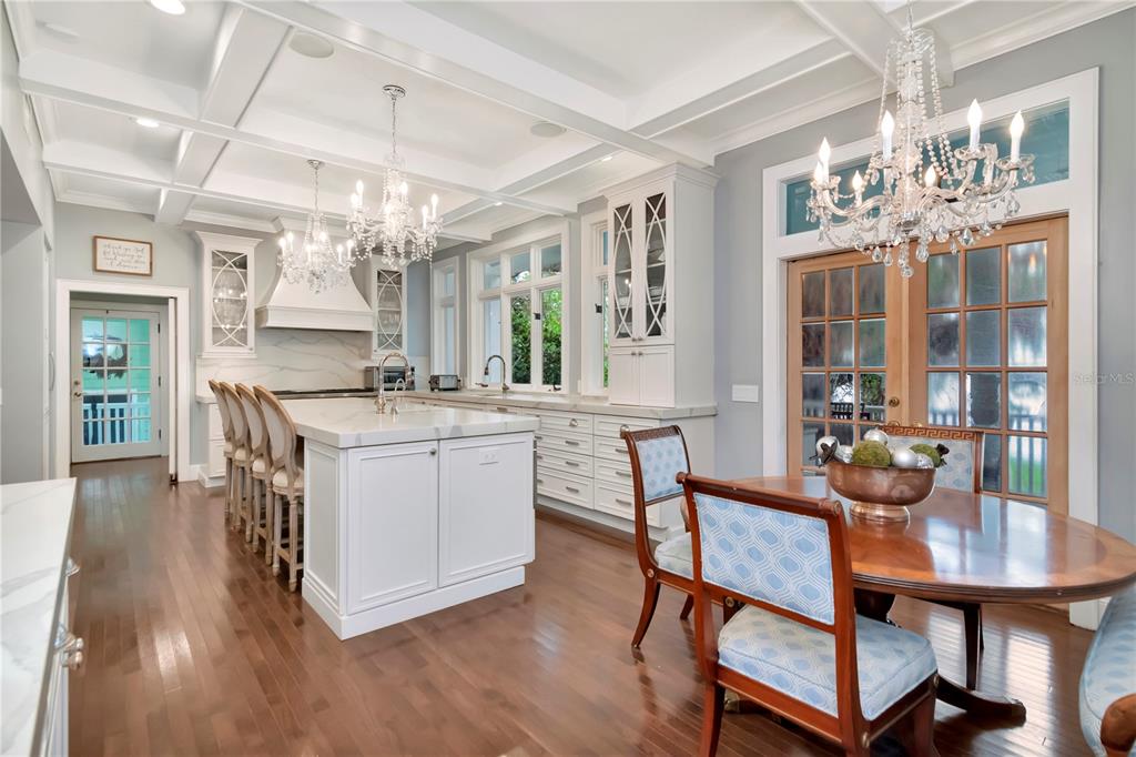 A kitchen with white cabinetry, a marble-topped island, chandeliers, and a dining area — 6220 BAYSHORE BOULEVARD, TAMPA, FL
