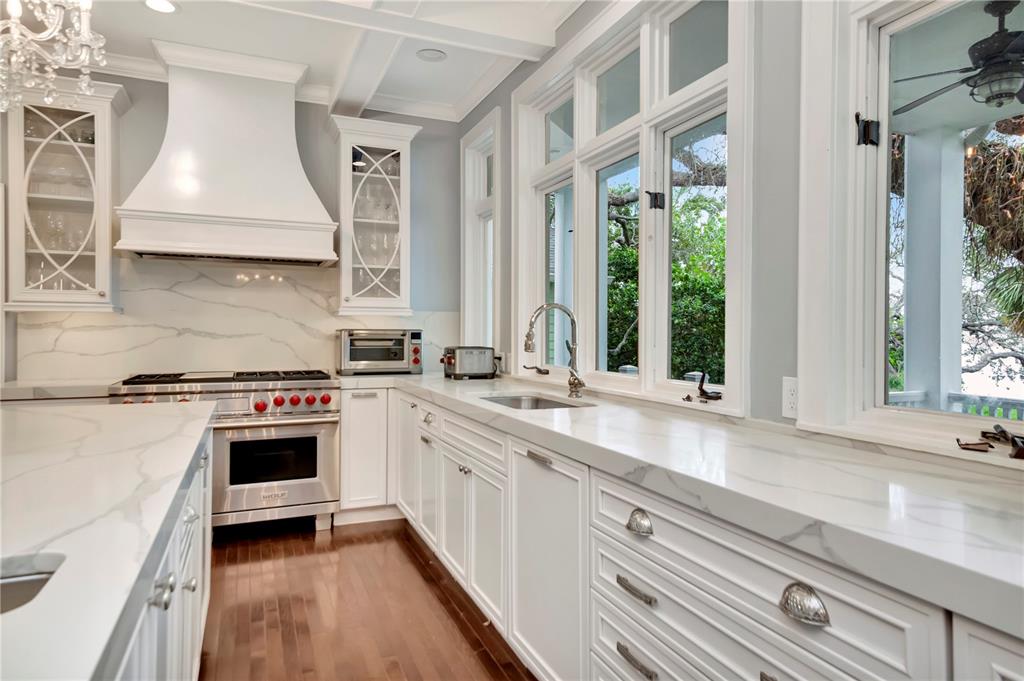 A kitchen features white cabinetry, marble countertops, a stainless steel range, and large windows — 6220 BAYSHORE BOULEVARD, TAMPA, FL