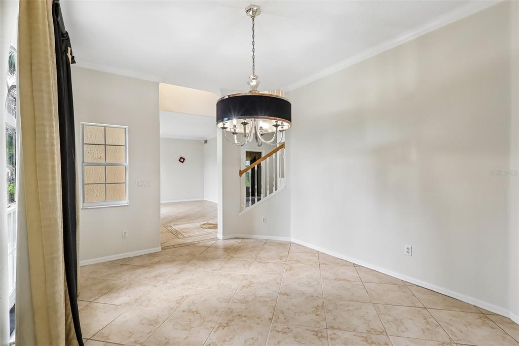 A dining room with tiled floors, a black drum chandelier, and a staircase in view — 2626 TETON STONE RUN, ORLANDO, FL