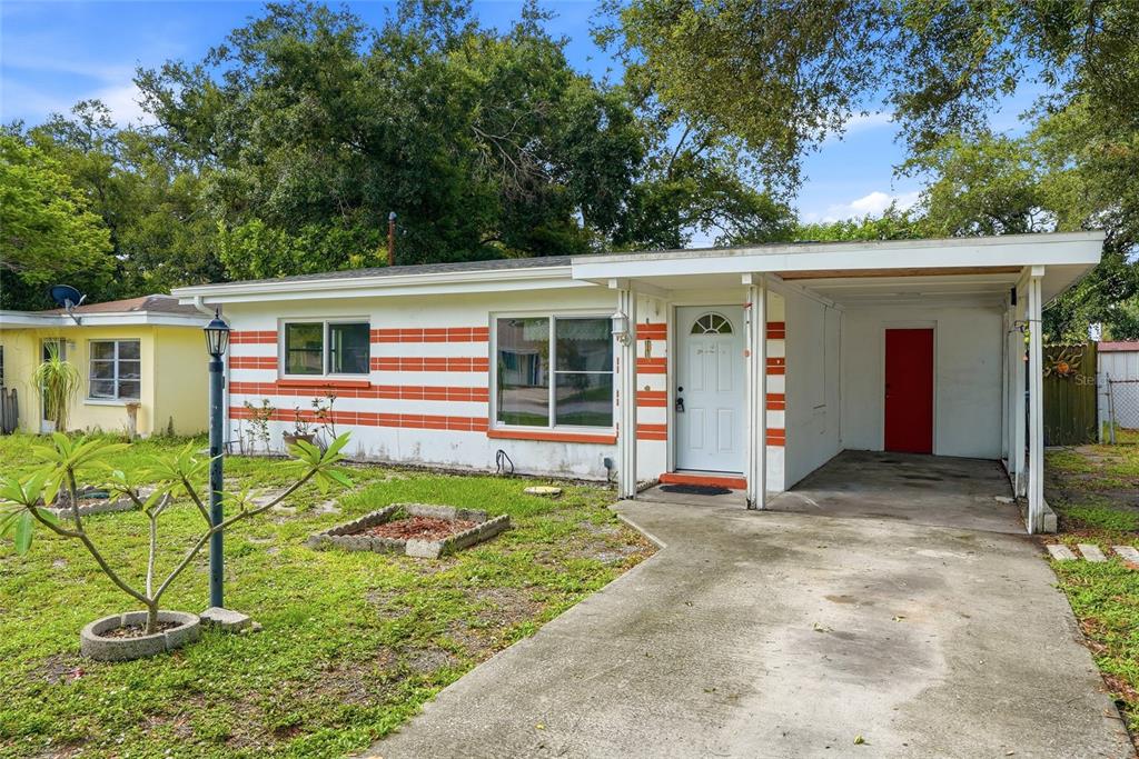 A single-story house with a white and orange striped exterior and an attached carport — 427 1ST AVENUE NE, LARGO, FL