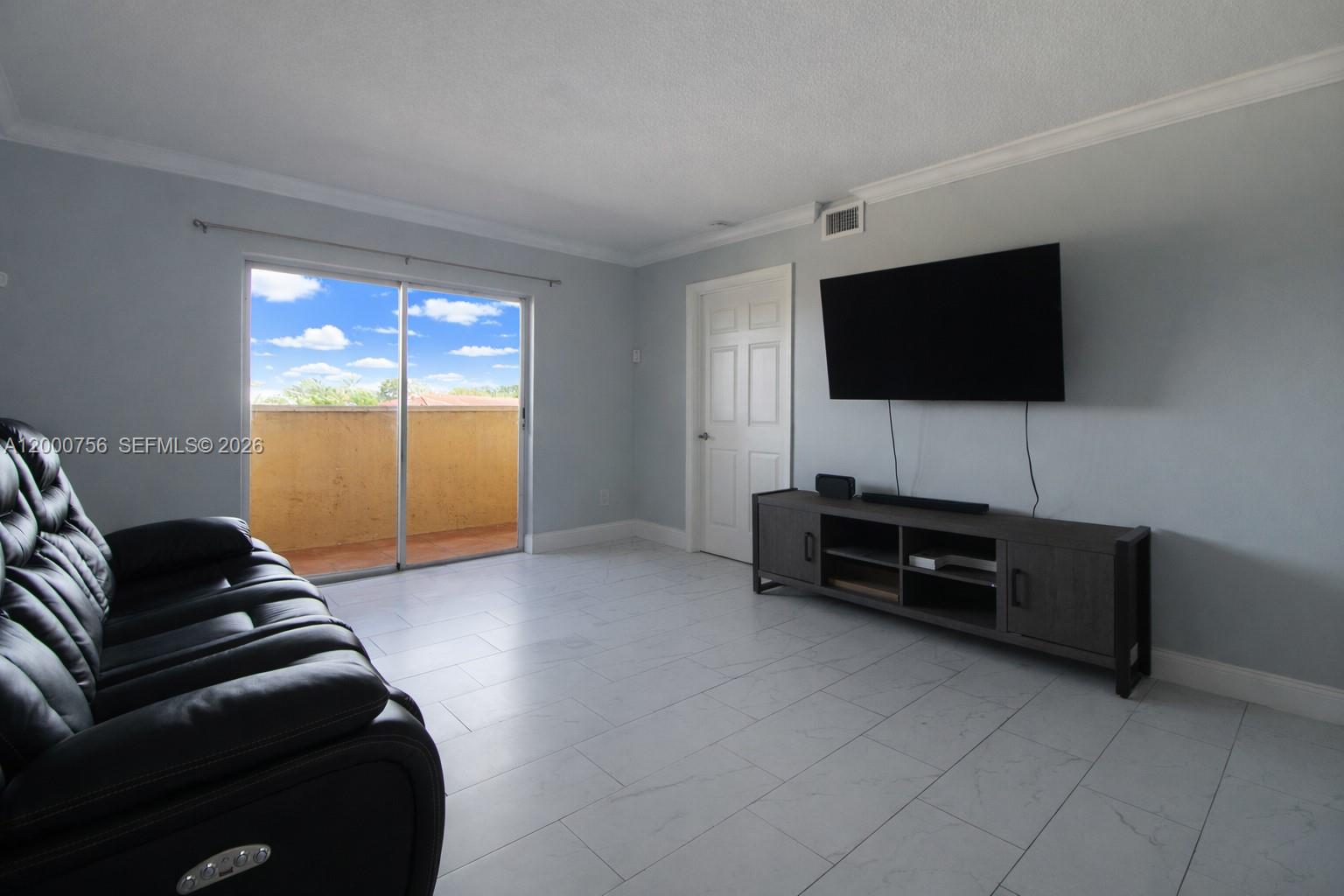 A living room features light gray walls, white tile flooring, a black sofa, and a balcony — 14951 SW 82nd Ln # 402, Miami FL 33193, MIAMI, FL