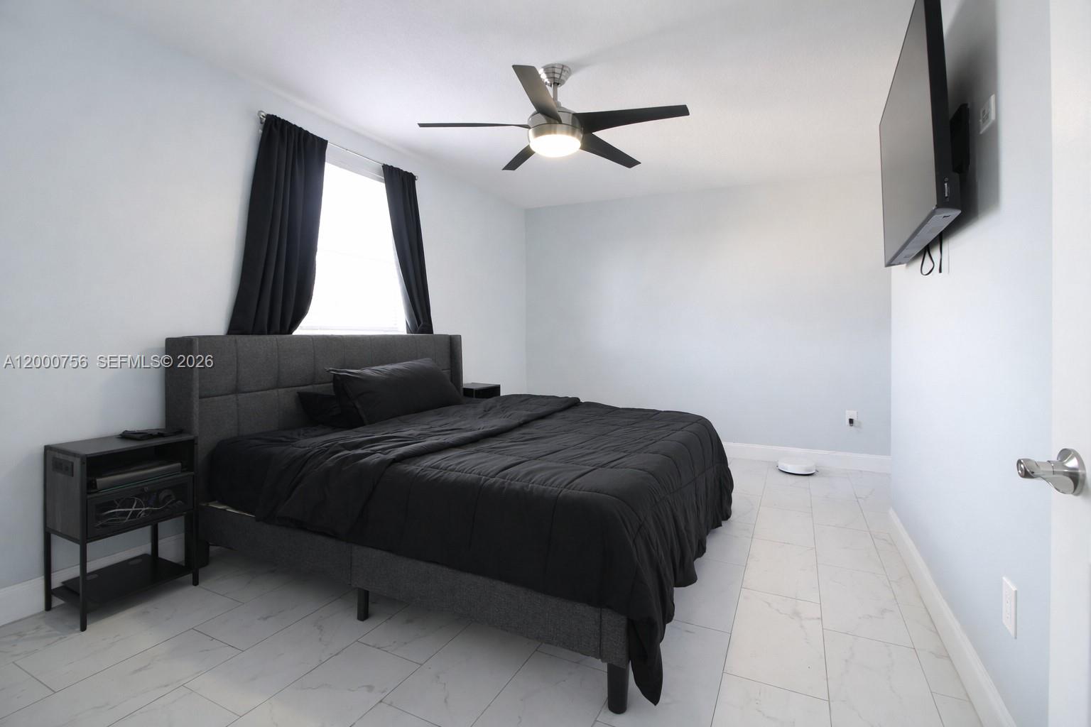 A bedroom features a dark upholstered bed, black bedding, a ceiling fan, and tiled floors — 14951 SW 82nd Ln # 402, Miami FL 33193, MIAMI, FL