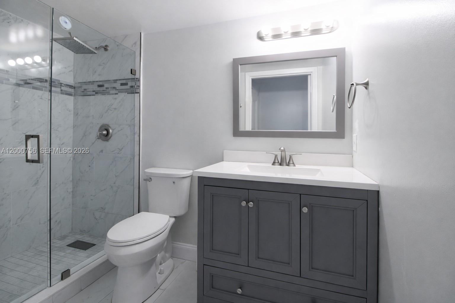 A bathroom features a gray vanity, a white countertop, a toilet, and a glass-enclosed shower — 14951 SW 82nd Ln # 402, Miami FL 33193, MIAMI, FL