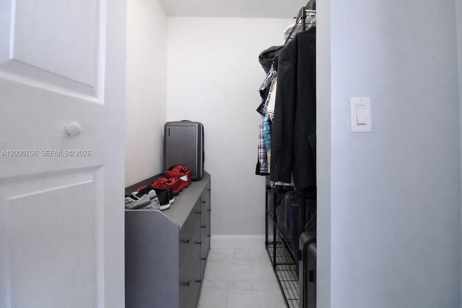 A walk-in closet features a gray dresser, wire shelving with hanging clothes, and tile flooring — 14951 SW 82nd Ln # 402, Miami FL 33193, MIAMI, FL