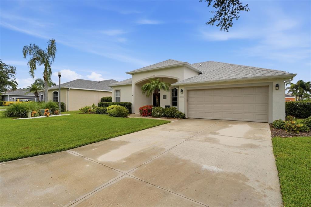 A single-story suburban house with a beige stucco exterior, a two-car garage, and a driveway — 12506 25TH COURT E, PARRISH, FL