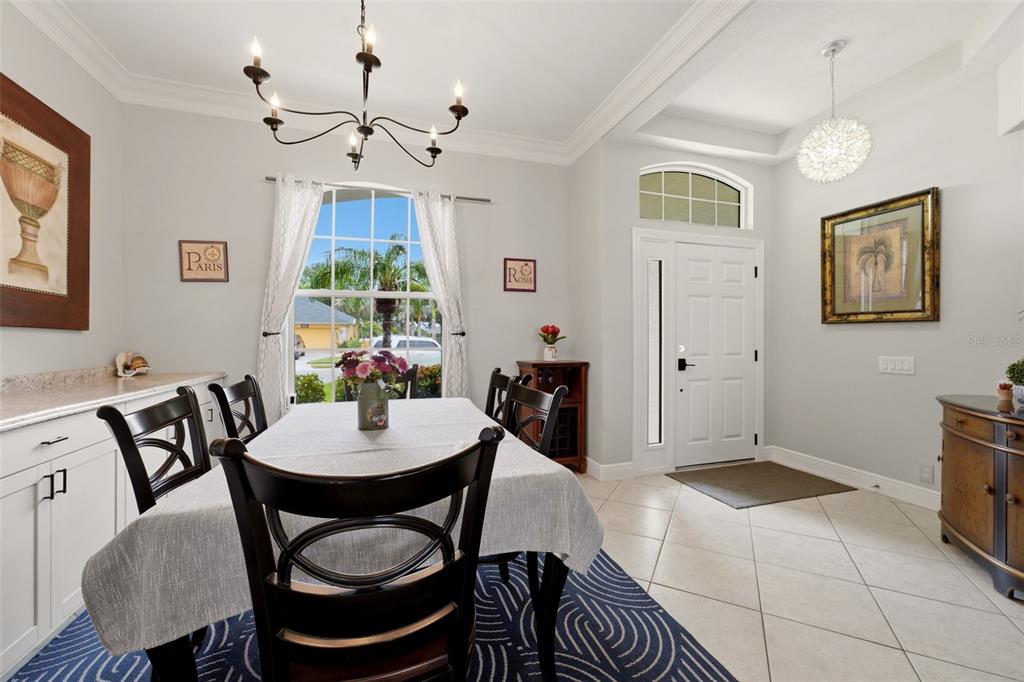 A dining room features a table, chandelier, tile floors, and an adjacent entryway — 12506 25TH COURT E, PARRISH, FL