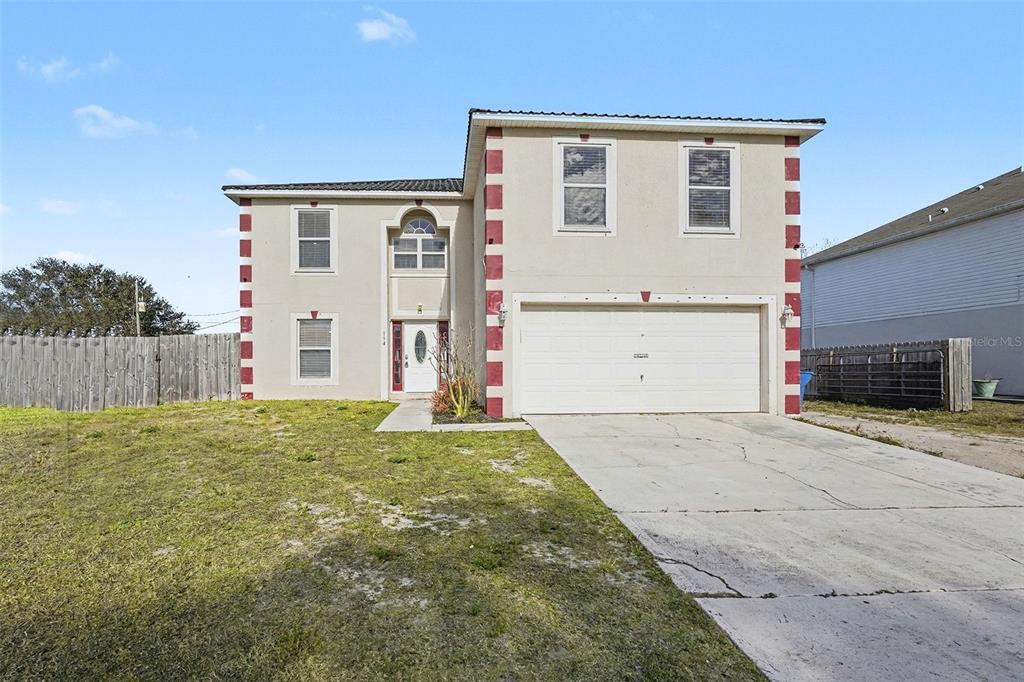 A two-story house with a beige stucco exterior, red corner accents, and a two-car garage — 194 ABALONE ROAD NW, PALM BAY, FL